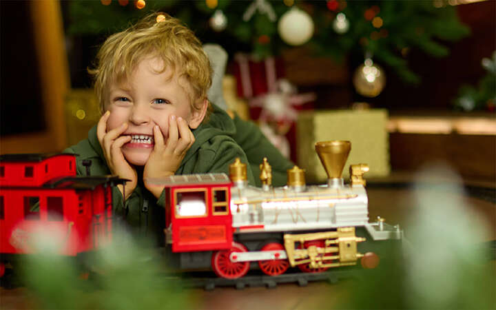 kind tannenbaum im hintergrund spielt mit eisenbahn 800x500